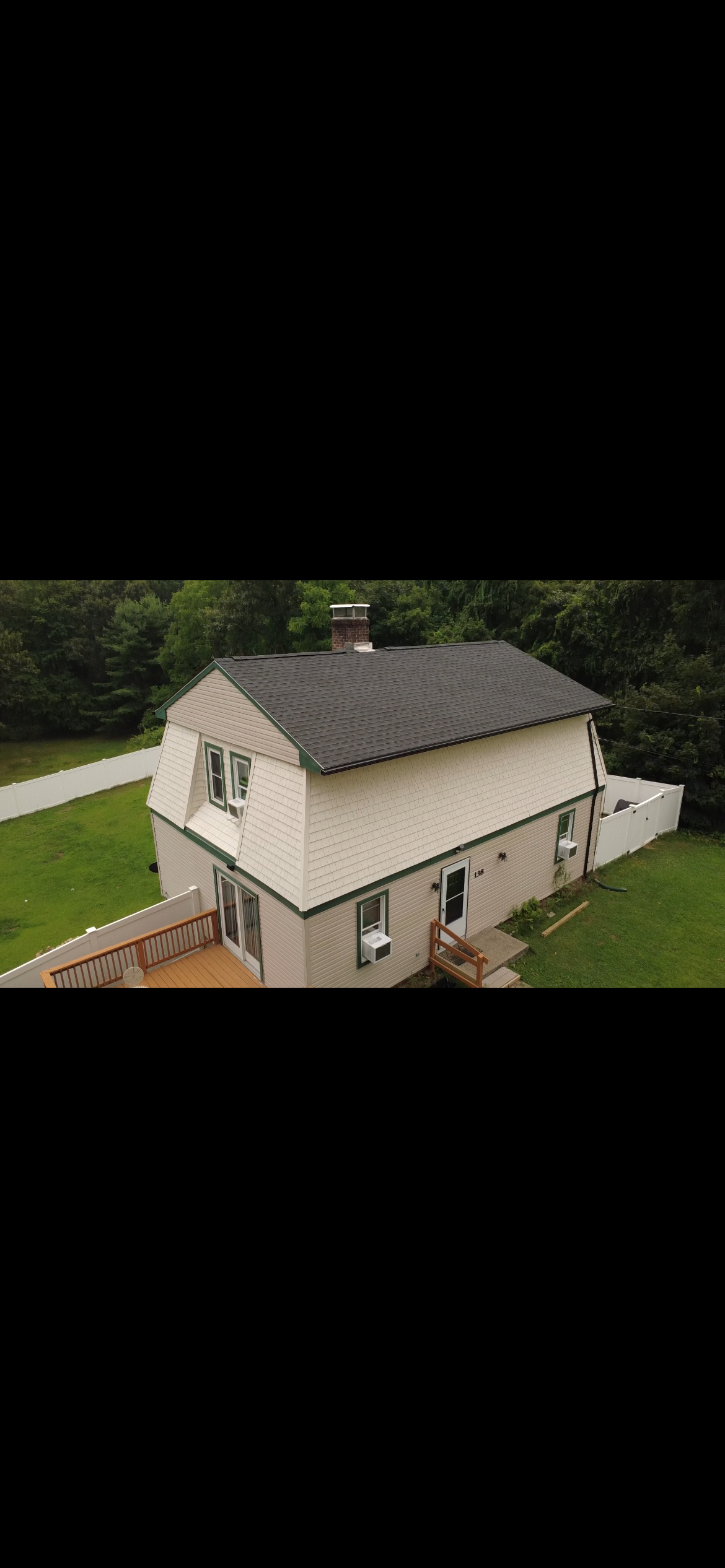 Gambrel roof replaced with dark architectural shingles, drone view