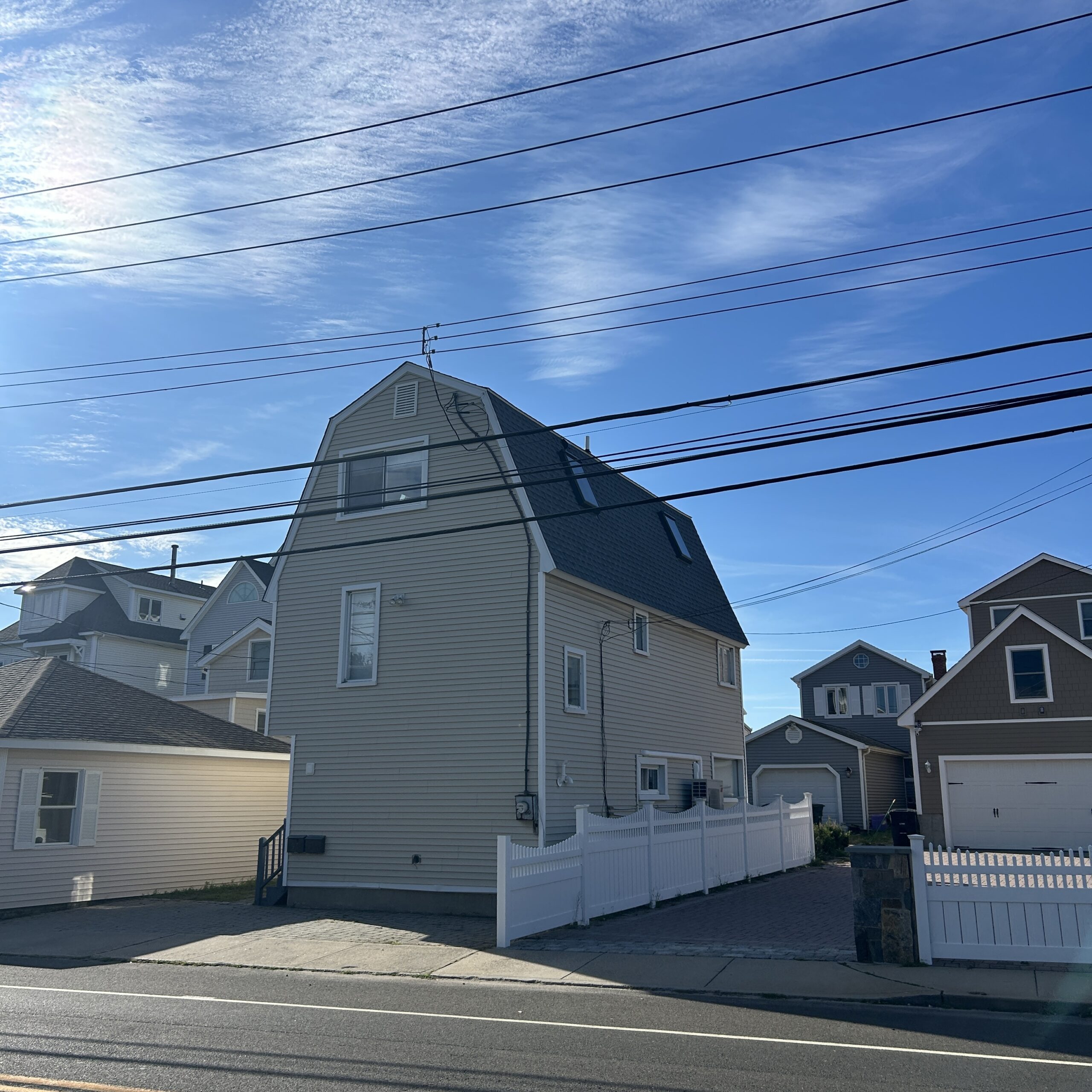 Gambrel-roof house with new dark shingles, street view