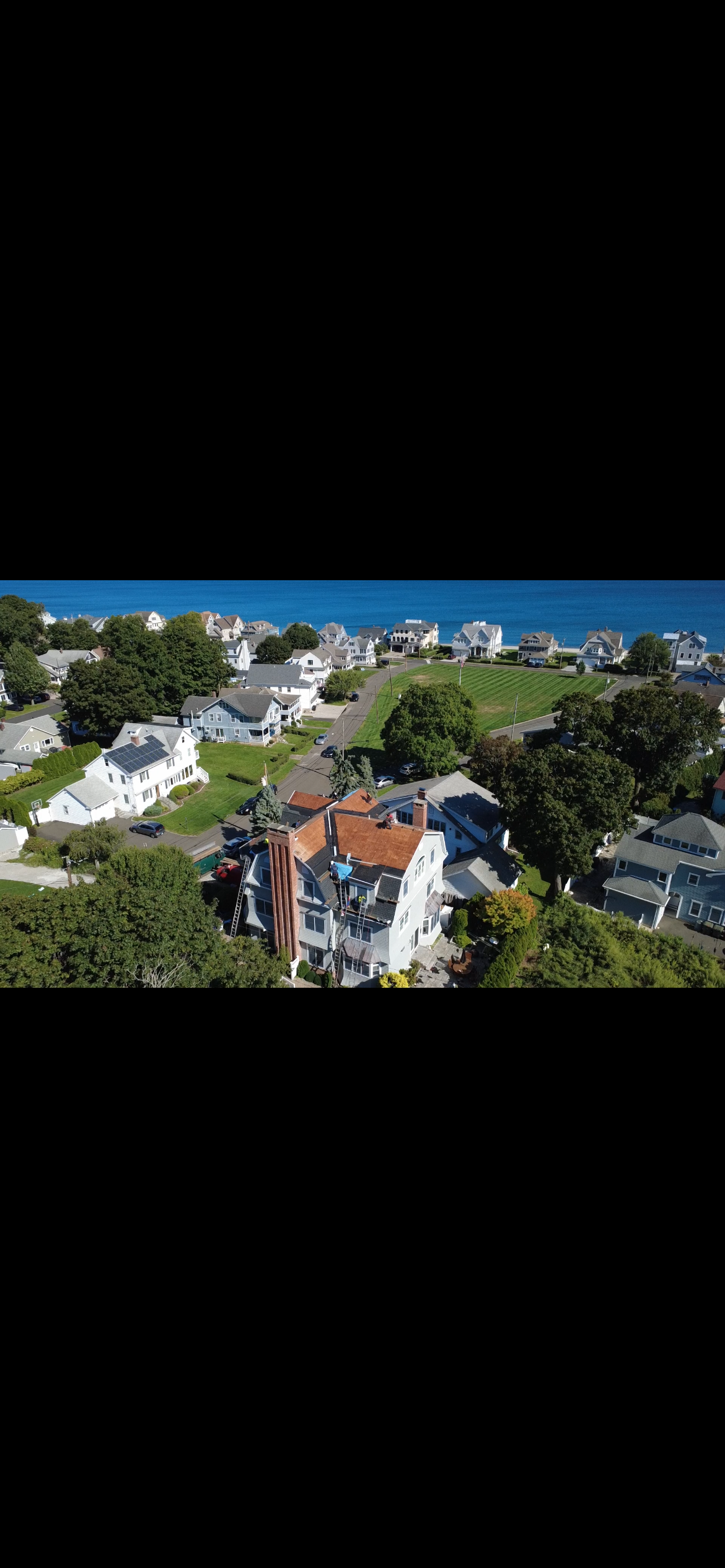 Aerial view of a shoreline neighborhood on Long Island Sound with a finished roof