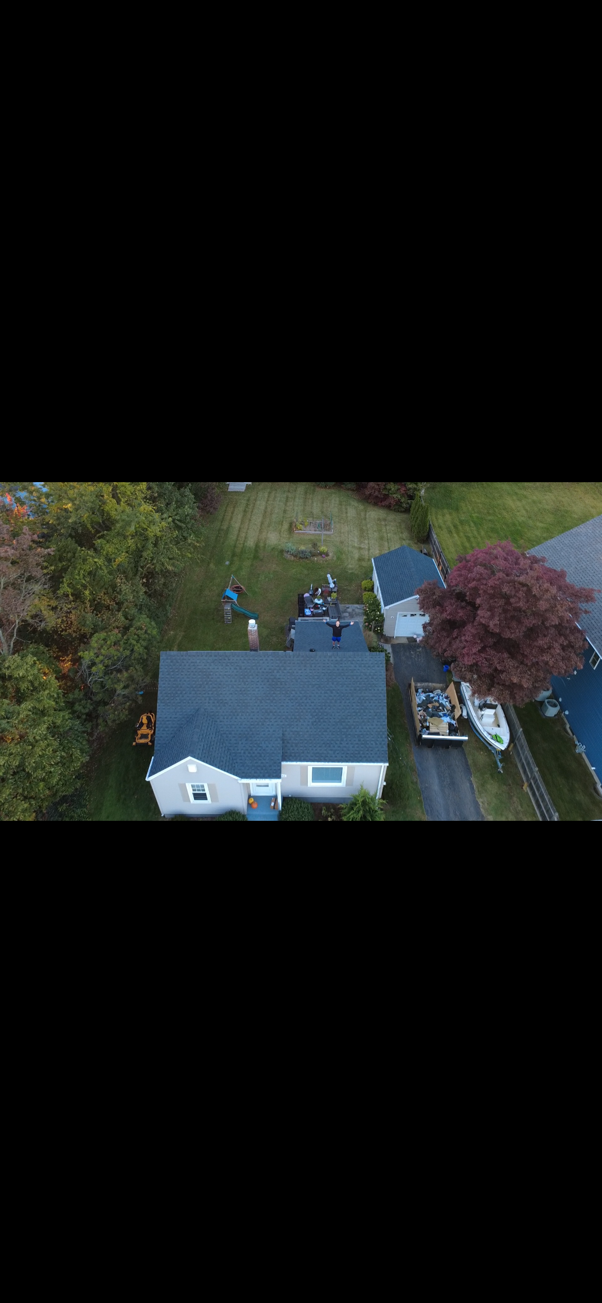 Cape home with a new dark shingle roof and gutters, aerial view