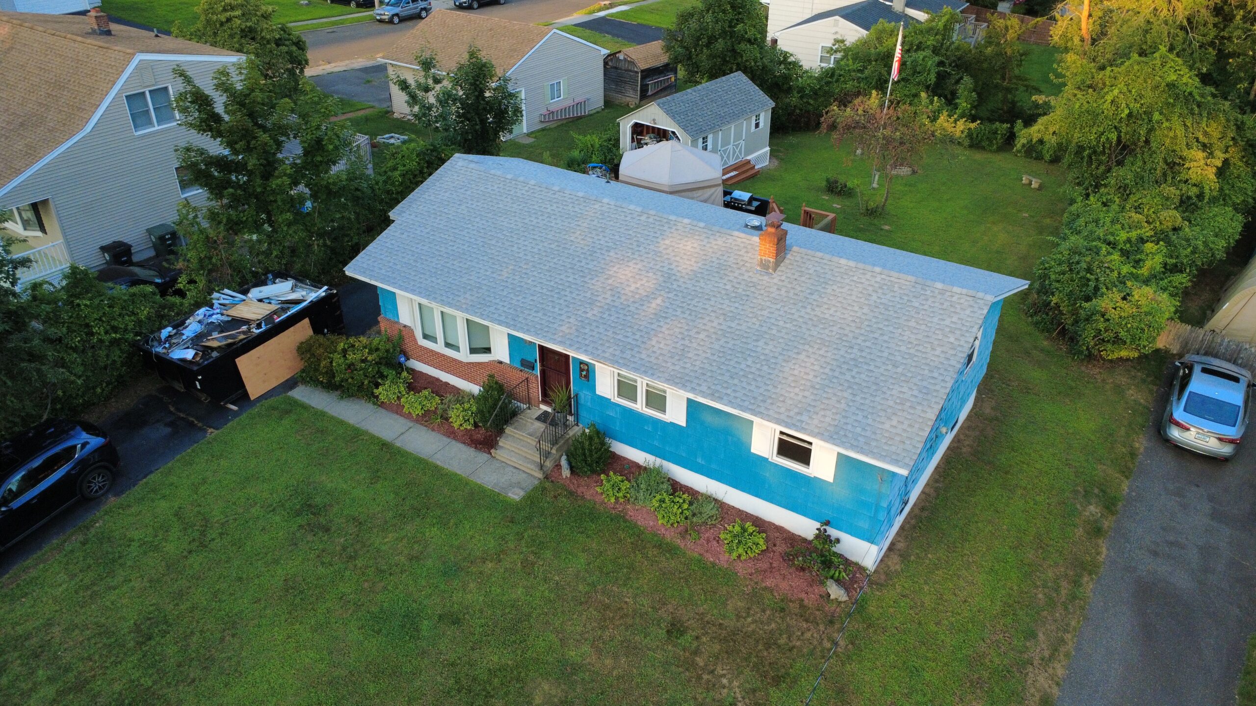 Drone view of a blue Cape-style home with a new light gray architectural shingle roof